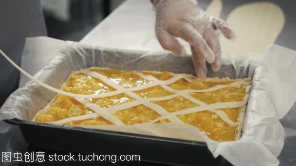 人準備水果橙色檸檬餡餅在廚房桌上, 最后的裝飾在手套, 餐廳廚房烘焙產品工廠